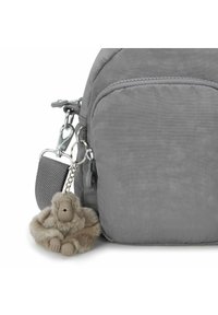 Bolsa de tela gris con un acabado texturizado, que cuenta con un bolsillo con cremallera y un accesorio para llaves con una figura de un mono peludo.