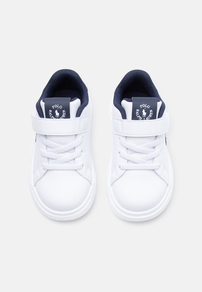 Par de zapatillas blancas para niños con interiores azul marino, tiras de velcro, cordones y logo de Polo Ralph Lauren en las lengüetas.