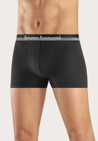 Svarta boxertrosor i mjuk tyg, med ett grått elastiskt midjeband som har "bruno banani"-logotyp. Slät textur och figurnära passform.