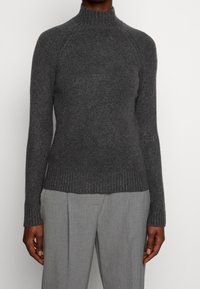 Grå ulltröja med hög krage och ribbad fåll samt manschetter, med en åtsittande design och raglanärmar.