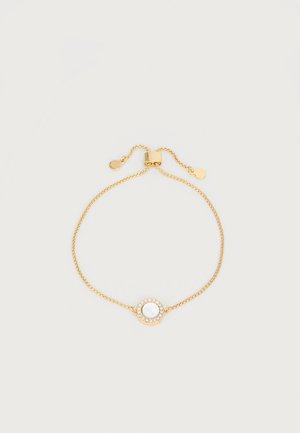 Arany állítható lánc karkötő, középen kör alakú fehér kővel, amelyet apró, tiszta kristályok vesznek körül.