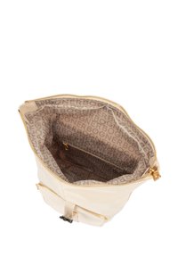 Kremfarvet taske med lynlåslukning, der har en blød tekstur og guldfarvet hardware. Indersiden har et gentagende logomønster i beige.