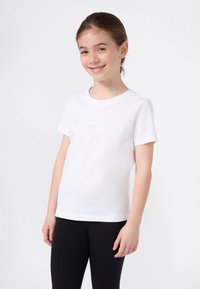 Witte katoenen t-shirt met korte mouwen, ronde halslijn, featuring een verhoogd 'Champion' logo over de borst. Gepaard met zwarte leggings.