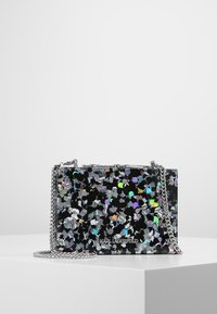 Borsa rettangolare nera con design di coriandoli metallici multicolori, tracolla in catena argento e dettaglio del logo sulla parte anteriore. Texture liscia.