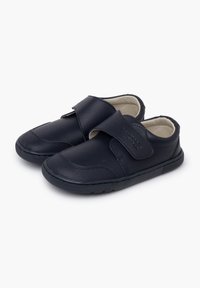 Une paire de chaussures noires pour enfants avec des brides Velcro, des embouts texturés et des intérieurs beiges rembourrés, présentée sur un fond blanc.