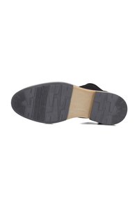 Zwarte schoen met een getextureerde rubberen zool, voorzien van een gladde tan accent nabij de hak en een onderscheidend profiel voor grip.