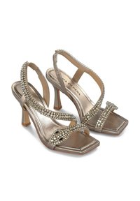 Sandali con tacco oro metallici, con punta quadrata, decorati con strass, dotati di cinturini incrociati alla caviglia e di un tacco a blocco di 7 cm.