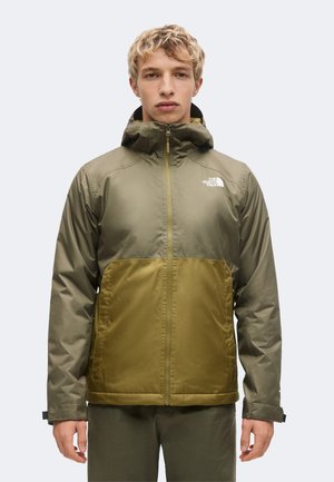 Jonge man die naar voren kijkt, draagt een tweekleurige groene North Face capuchonjas met ritssluiting aan de voorkant en een logo op de borst.