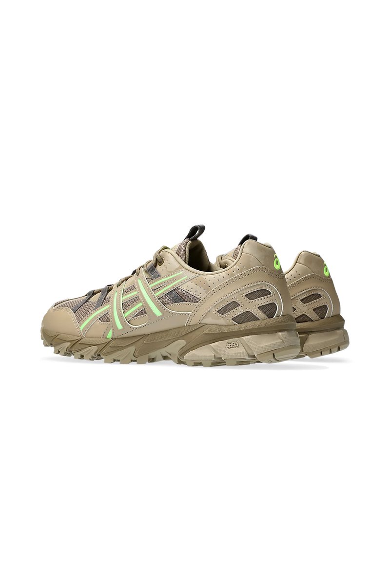 Zapatillas deportivas beige con materiales de malla y sintéticos, destacadas por acentos en verde neón, suela resistente y un diseño curvado.