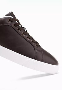 Sneaker in pelle marrone con punta rotonda, suola in gomma bianca e lacci neri a contrasto. Texture liscia con dettagli di cucitura sottili.