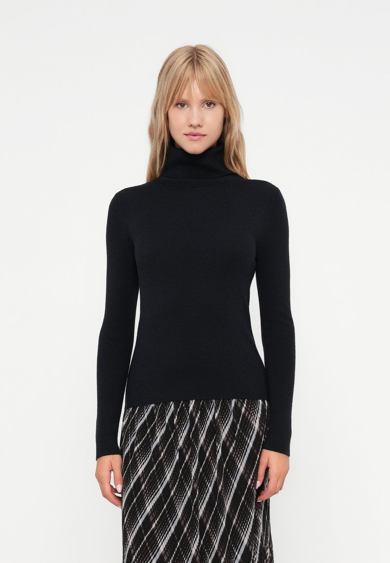 Suéter negro de cuello vuelto con mangas largas, hecho de un material de punto suave. Diseño ajustado que se extiende hasta las caderas, combinado con una falda de estampado.