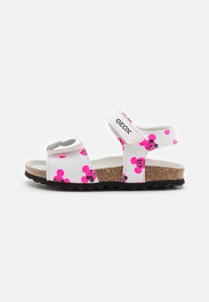Sandalias blancas con patrones de Mickey Mouse en rosa y negro, plantilla de corcho, correas ajustables y suela de goma texturizada.