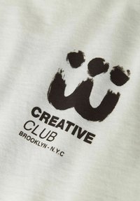 White fabric with a large black graphic logo featuring a stylized "w" and text "CREATIVE CLUB BROOKLYN - N.Y.C" in bold.