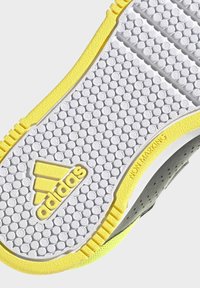 Suela de zapato Adidas con patrón circular de tracción, base blanca y acentos amarillo brillante, con texto "NON MARKING" en el lateral.