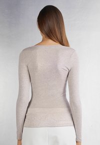 Helles graues Langarmoberteil mit Rundhalsausschnitt. Figurbetonter Schnitt und weiche Textur, von hinten vor einem neutralen Hintergrund gezeigt.