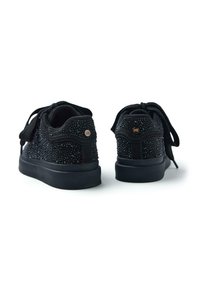 Sneakers neri con una parte superiore textured e dettagli borchiati, lacci rotondi e una suola in gomma nera con una leggera elevazione.
