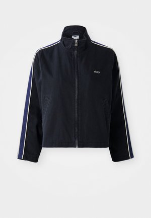 Navy blue jacket with a high collar, white side stripes, and zip closure. Features two front pockets and an embroidered logo on the chest.
