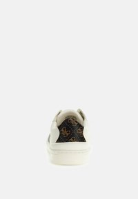 Zapato casual blanco con un respaldo texturizado que presenta un patrón de monograma en marrón y negro. Suela de goma, forma redondeada y diseño minimalista.