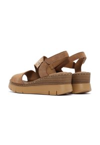 Brown suede wedge sandals with open toe, adjustable strap, and textured outsole. Features a stitched accent around the sole.