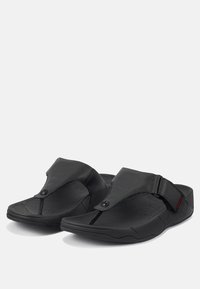 Sandales noires avec un design à orteil fendu, dotées d'une sangle ajustable, d'une tige en cuir texturé et d'une semelle en caoutchouc profilée pour le confort.