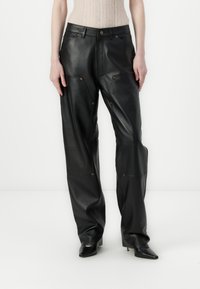 Czarne skórzane spodnie o luźnym kroju, z widocznymi szwami, złotymi detalami i wysokim stanem. Gładka faktura z minimalnymi zdobieniami.