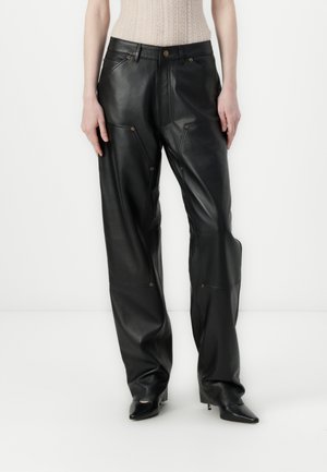 Pantalones de piel negra con un corte holgado, que presentan costuras visibles, detalles en dorado y una cinturilla alta. Textura lisa con un mínimo de detalles.