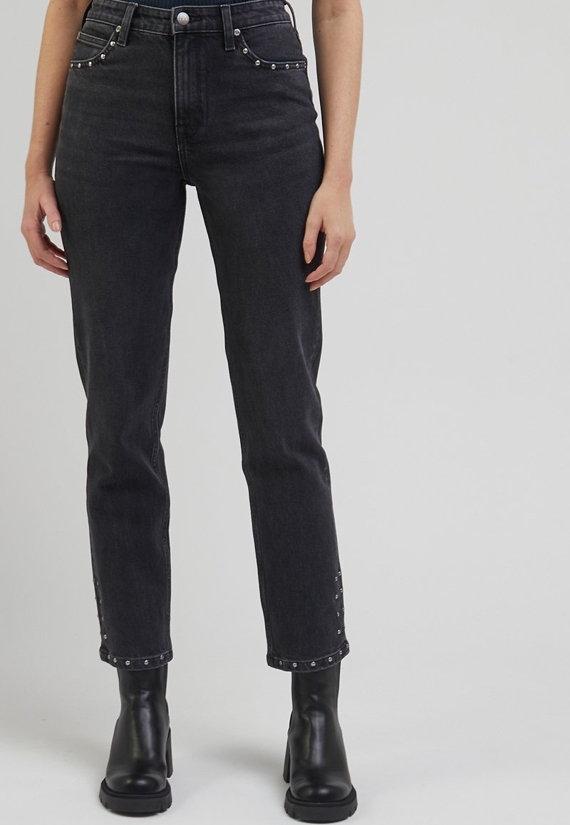 Mustat denimit, joissa on suora lahje, etupusseissa ja helmassa hopeiset niitit. Yhdistettyinä paksupohjaisiin mustiin korkokenkiin.