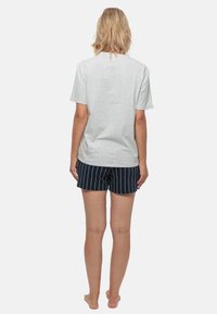 Lichtgrijze t-shirt met korte mouwen gezien van achteren, gecombineerd met marineblauwe gestreepte shorts. Eenvoudig ontwerp, losse pasvorm en zachte stof.