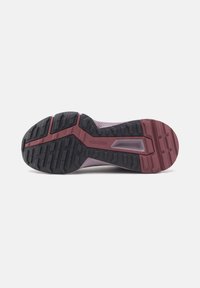Schuhsohle mit schwarzem und dunkelrotem Gummiprofil, mit tiefen Rillen und "TRAXION"-Text für verbesserten Grip und Traktion.