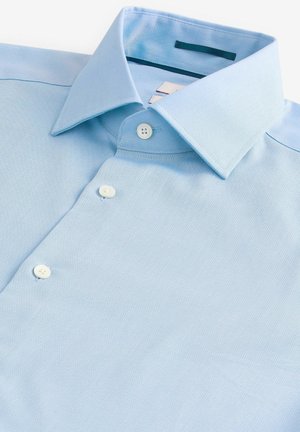 Light blue button-up shirt made of textured fabric, featuring a classic collar and three buttons at the front. No patterns visible.