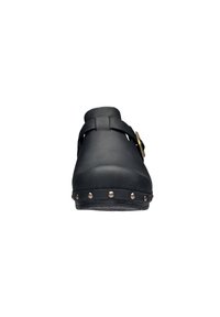 Zoccoli neri con punta arrotondata, realizzati in gomma, dotati di una cinghia con una fibbia in ottone. La suola ha borchie di metallo lungo il bordo.