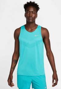 Una camiseta sin mangas de Nike en un tono turquesa brillante con un patrón texturizado, que presenta un cuello redondo y un ajuste ceñido, combinada con pantalones cortos a juego.