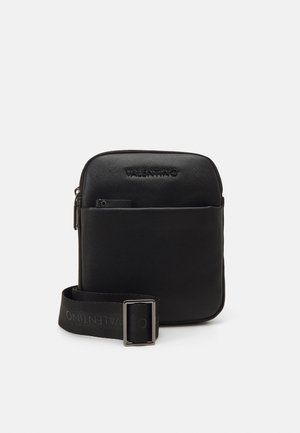 Sac bandoulière Valentino noir avec poche avant et sangle réglable avec boucle métallique sur fond uni.