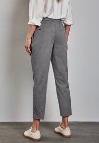 Grå korta byxor i lätt tyg, med avslappnad passform, bakfickor och enkel design. Sammanställda med beige avslappnade skor.