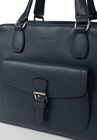 Borsa a mano in pelle blu scuro con superficie testurizzata, doppi manici e tasca frontale con patta e dettagli in metallo argentato.