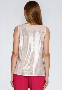 Bezrękawnik w jasnoróżowym kolorze, pokryty cekinami. Gładka faktura i luźny krój, z zaokrąglonym dekoltem i prostym dołem.