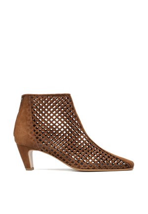 Brązowy zamszowy botek za kostkę na niskim obcasie z otwartym, kratkowanym wzorem pokrywającym boki i górę, z ostrym noskiem i zamkiem z tyłu.