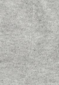 Tessuto grigio chiaro lavorato a maglia con una texture morbida, caratterizzato da un motivo sottile e una finitura liscia, adatto per abbigliamento o accessori.