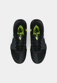 Μαύρα αθλητικά παπούτσια από πλέγμα και συνθετικά υλικά, με νεον πράσινες λεπτομέρειες και υφές στην επάνω επιφάνεια και στην σόλα.