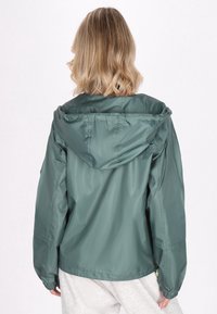 Jachetă verde ușoară cu glugă, manșete elastice și croială relaxată. Textură netedă și strălucitoare, proiectată pentru îmbrăcăminte casual.