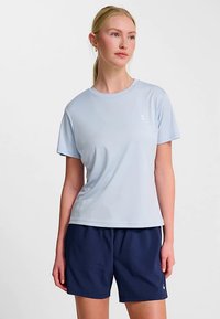 Jasnoniebieska sportowa koszulka z krótkimi rękawami i okrągłym dekoltem, w połączeniu z granatowymi szortami, z małym logo na piersi.