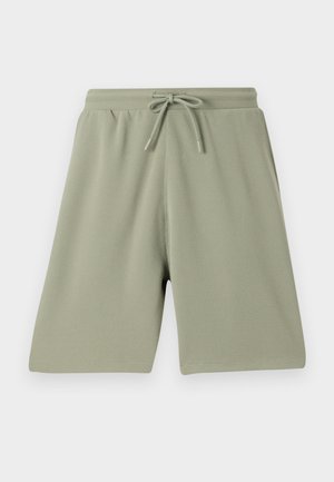 Calções verdes claros feitos de um tecido texturado com cintura elástica e cordão. Corte reto e design até ao joelho.