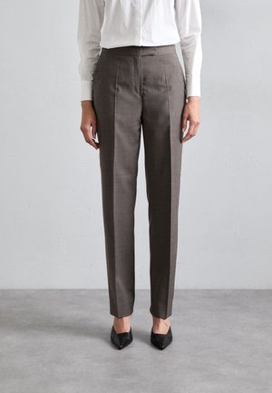 Brown tailored trousers with a straight leg design, subtle texture, and pleats, paired with black pointed-toe heels.