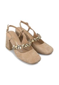 Zapatos de tacón cuadrado de ante beige, con puntera cuadrada, que cuentan con una tira decorativa de piedras preciosas transparentes y doradas a lo largo del empeine.