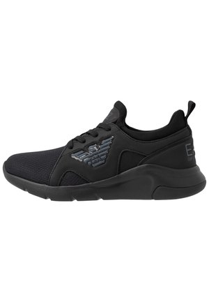 Czarny niski sneaker z zapięciem na sznurówki, teksturowanym materiałowym noskiem, grubą podeszwą i refleksyjnym logo orła z boku.