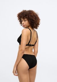 Svart ribbad bikini med triangul topp och högmidjad bottom. Inkluderar justerbara remmar och subtila sömnadsdetaljer.