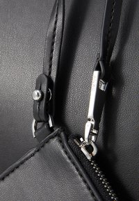 Black leather bag featuring textured finish, silver hardware, and a zip closure. Notable details include a clip and stitching accents.