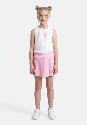 Jong meisje met blond haar in dubbele knotjes en vlechten, draagt een wit mouwloos topje, een roze geplooide rok en witte sneakers met roze accenten.