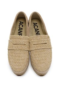 Scarpe slip-on beige realizzate in paglia intrecciata con una finitura texturizzata. Presentano una suola piatta e un design semplice senza ulteriori decorazioni.