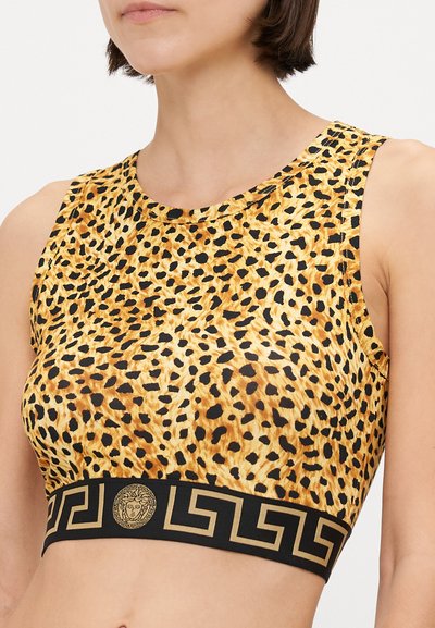 Dzeltenā un melnā leoparda raksta īsā tops ar apaļu kakla izgriezumu. Melnais pārsējs ir dekorēts ar zelta Grieķijas atslēgu rakstu un logotipa detaļām.